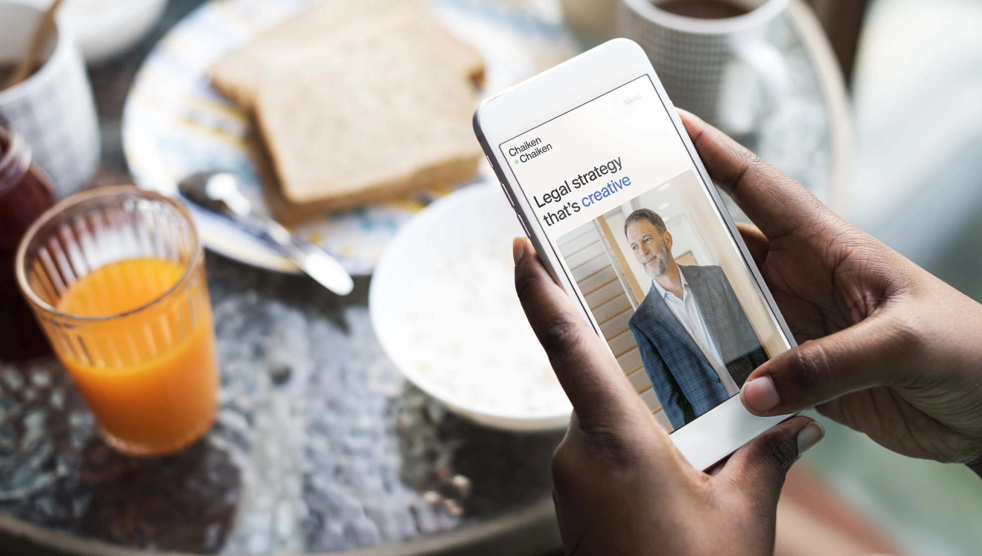 Person holding a smartphone displaying the Chaiken & Chaiken homepage with the headline