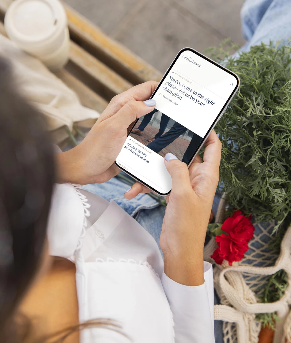 Person holding a smartphone displaying the Gideon Asen law firm homepage with the headline