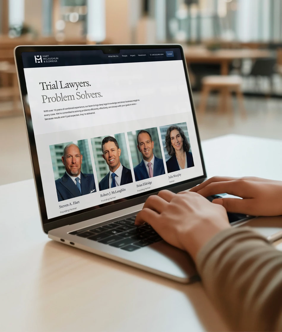 Hart McLaughlin & Eldridge People page displayed on a MacBook laptop, showing headshots and names of founding partners Steven A. Hart, Robert J. McLaughlin, Brian Eldridge, and partner Julie Murphy